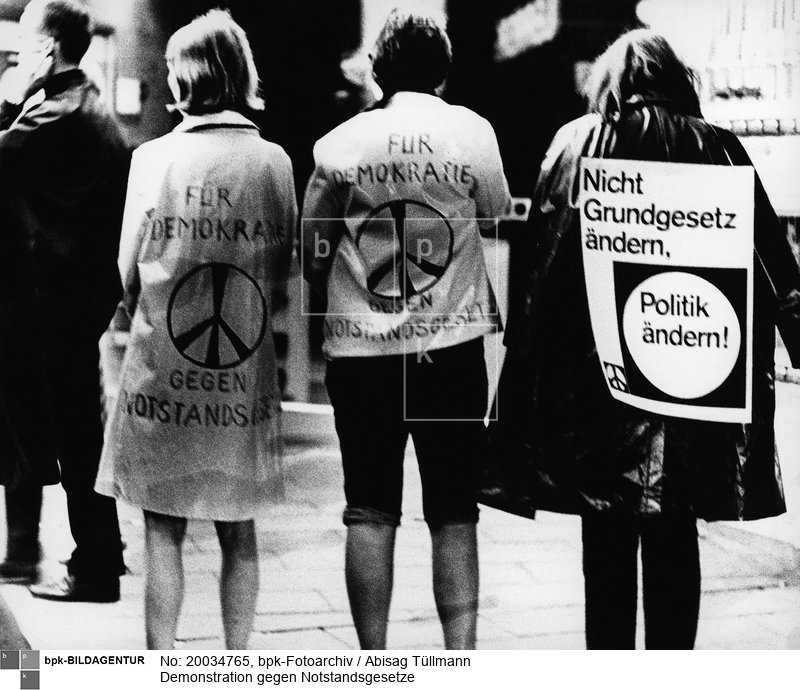 Eine Demonstrantin trägt ein Rückenplakat mit der Aufschrift: "Nicht Grundgesetz ändern, Politik ändern!" (Scan vom Vintageprint)<BR>Aufnahmedatum: 1967<BR>Material/Technik: Foto<BR>Aufnahmeort: Bonn / Deutschland<BR>Inventar-Nr.: Tü 67/068-36a<BR>