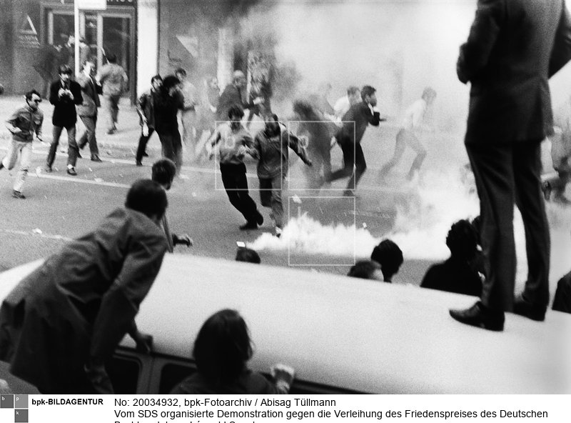 Auf der Berliner Straße kicken Demonstranten die von der Polizei geworfenen Tränengasbehälter in Richtung Polizei zurück. Der senegalesische Staatspräsident und Schriftsteller Léopold Sédar Senghor wird der Kolloboration mit dem Kolonialismus beschuldigt. (Scan vom Vintageprint)<BR>Aufnahmedatum: 22.09.1968<BR>Material/Technik: Foto<BR>Aufnahmeort: Frankfurt am Main / Deutschland<BR>Inventar-Nr.: Tü 68/226-02<BR>