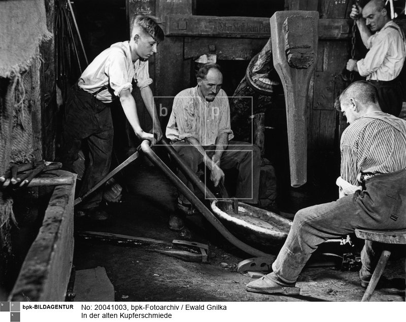 Fotograf: Ewald Gnilka <BR> Mit einem großen, wasserbetriebenen Hammer formen die Kupferschmiede eine Schüssel. <BR> Motiv 3 von 11 <BR> Aufnahmedatum: um 1930 <BR> Inventar-Nr.: Gk 2621 <BR> Systematik:  <BR> Kulturgeschichte / Handwerk / Metallgewerbe / Schmied / Kupferschmied