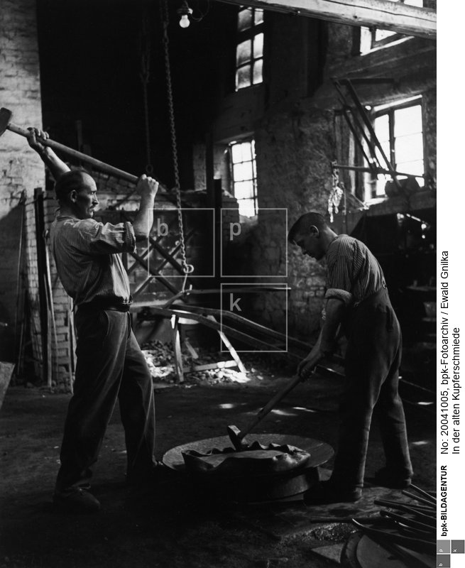 Fotograf: Ewald Gnilka <BR> Mit weit ausholendem Schlag wird das Kupferblech in Form gebracht. <BR> Motiv 5 von 11 <BR> Aufnahmedatum: um 1930 <BR> Inventar-Nr.: Gk 2618 <BR> Systematik:  <BR> Kulturgeschichte / Handwerk / Metallgewerbe / Schmied / Kupferschmied