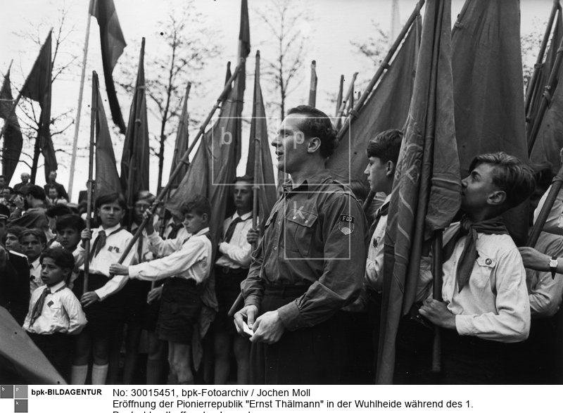 Fotograf: Jochen Moll <BR> Der Vorsitzende der FDJ, Erich Honecker, überreicht an die Teilnehmer der Veranstaltung Fahnen für aktive Mitarbeit in der Kinderorganisation "Junge Pioniere". <BR> Motiv 2 von 3 <BR> Aufnahmedatum: Mai 1950 <BR> Aufnahmeort: Berlin (Ost) <BR> Inventar-Nr.: Mo 0084-32 <BR> Systematik:  <BR> Geschichte / Deutschland / 20. Jh. / DDR / Bevölkerung / Jugendliche / FDJ / Allgemeines / Erich Honecker