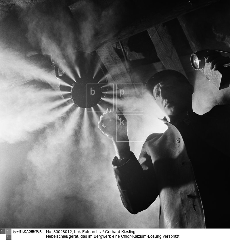 Durch die entstehende künstliche Nebelwand soll der Staub gebunden werden und somit Silikose bei Bergleuten verhindert werden<BR>Aufnahmedatum: 1954<BR>Material/Technik: Foto<BR>Inventar-Nr.: Ks 0687/2-08<BR>