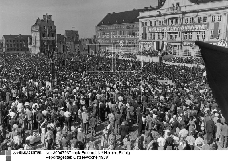 5.-13. Juli 1958; vgl. DDR 9/1958, S. 22 ("Woche des Friedens"): "Rostock, 5. Juli 1958. 16 Uhr. Hunderttausend Menschen aus den Anliegerstaaten der Ostsee hatten sich auf dem Ernst-Thälmann-Platz versammelt. Sie waren sich darüber einig, daß die Ostsee für alle Zeiten ein Meer des Friedens sein muß. Die Voraussetzungen hierfür sind durchaus vorhanden, meinte der Erste Sekretär der Sozialistischen Einheitspartei Deutschlands und Stellvertreter des Vorsitzenden des Ministerrats der DDR, Walter Ulbricht, in seiner Eröffnungsansprache."; Neuer Markt (1952-1991: Ernst-Thälmann-Platz), Rostocker Rathaus<BR>Aufnahmedatum: 05.07.1958<BR>Material/Technik: Foto<BR>Aufnahmeort: Rostock, Bezirk Rostock, DDR<BR>Inventar-Nr.: Fg 0523/18-14<BR>
