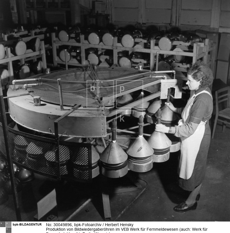 Fotograf: Herbert Hensky <BR> Versehen von Bildröhren mit Sockeln im Durchlaufofen <BR> Aufnahmedatum: 30.03.1954 <BR> Aufnahmeort: Berlin (Ost) <BR> Inventar-Nr.: Hy 0638/1571-05 <BR> Systematik:  <BR> Geschichte / Deutschland / 20. Jh. / DDR / Wirtschaft / Industrie / Elektrotechnische Industrie / einzelne Industriezweige / Rundfunk- und Fernsehgeräte