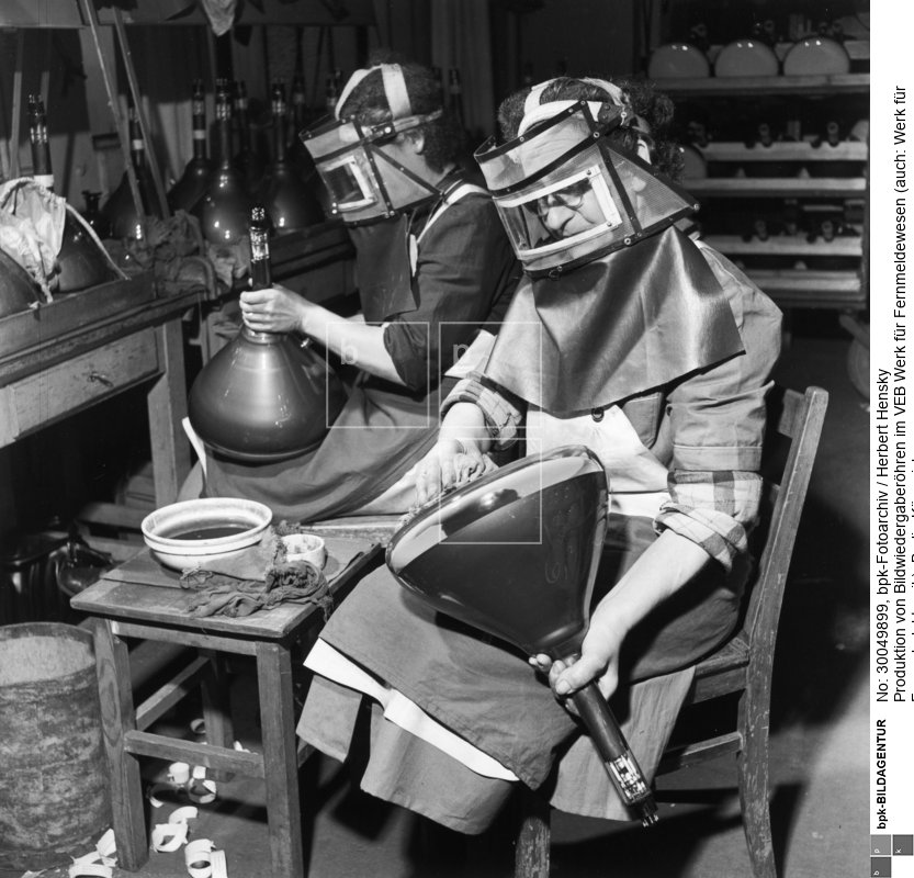 Fotograf: Herbert Hensky <BR> Säubern von Bildröhren mit Schutzmaske <BR> Aufnahmedatum: 30.03.1954 <BR> Aufnahmeort: Berlin (Ost) <BR> Inventar-Nr.: Hy 0638/1572-03 <BR> Systematik:  <BR> Geschichte / Deutschland / 20. Jh. / DDR / Wirtschaft / Industrie / Elektrotechnische Industrie / einzelne Industriezweige / Rundfunk- und Fernsehgeräte