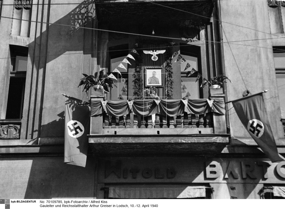 Während des dreitätigen Besuchs verkündete Greiser in seiner Rede in der Sporthalle (11. April 1940) die Umbenennung von Lodsch in Litzmannstadt. Hier: mit Hitler-Porträt, Adler und Hakenkreuzfahnen geschmückter Balkon, Rudolf-Hess-Straße (Ulica Główna) 52 (Kolonialwarenhandlung Witold Bartoszewicz)<BR>Aufnahmedatum: 10./11.04.1940<BR>Material/Technik: Foto<BR>Aufnahmeort: Lodz (Lodsch, 1940-45 Litzmannstadt), Reichsgau Posen (1939-40), Reichsgau Wartheland (1940-45), Deutsches Reich (durch Annexion) / Łódź, Polen<BR>Inventar-Nr.: Ki I/023/01<BR>