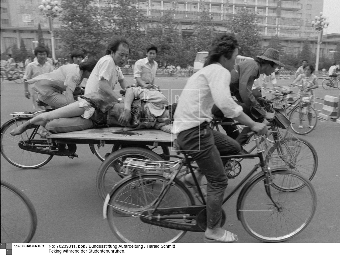 Soldaten auf Panzer haben nachts die demonstrierenden Studenten zusammengeschossen. Noch an frühen Morgen wird einfach in die Menschen geschossen. Die flüchten in Panik. Krankenwagen werden nicht durchgelassen um Verletzte zu bergen. Diese werden von Bürgern, auf Fährrädern, in die umliegenden Kliniken gebracht. 5. Juni 1989<BR>Aufnahmedatum: 05.06.1989<BR>Material/Technik: Foto<BR>Aufnahmeort: Peking / China<BR>Inventar-Nr.: 89 0606 001FV