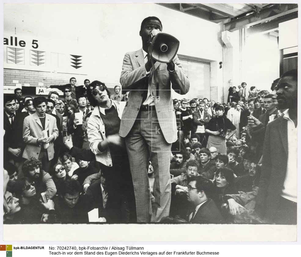 Starke Proteste begleiten 1968 die Verleihung des Friedenspreises des Deutschen Buchhandels an Leopold S. Senghor. Um weitere Demonstrationen zu verhindern, schließt die Messeleitung die Ausstellungshallen zeitweise für die Öffentlichkeit
Rückseitenbeschriftung von Hand der Fotografin: "Buchmesse 1968, vor dem Diederichs-Stand"<BR>Aufnahmedatum: September 1968<BR>Material/Technik: Foto / Silbergelatine auf Barytpapier<BR>Bildformat (Foto): 23,6 x 29,4 cm<BR>Aufnahmeort: Frankfurt am Main / Deutschland<BR>Inventar-Nr.: Tü 68/219-10a<BR>