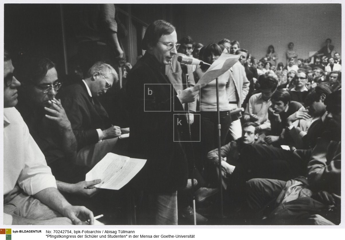 Hans-Jürgen Krahl am Mikrofon, hinter ihm sitzen Jürgen Habermas und Peter Brückner
Rückseitenbeschriftung von Hand der Fotografin: "Juni 1968, Ffm (Pfingstkongreß, H.J. Krahl am Mikrophon, hinter ihm sitzen Habermas und Brückner)"<BR>Aufnahmedatum: Juni 1968<BR>Material/Technik: Foto / Silbergelatine auf Barytpapier<BR>Bildformat (Foto): 19,6 x 30,3 cm<BR>Aufnahmeort: Frankfurt am Main / Deutschland<BR>Inventar-Nr.: Tü 68/090-28<BR>