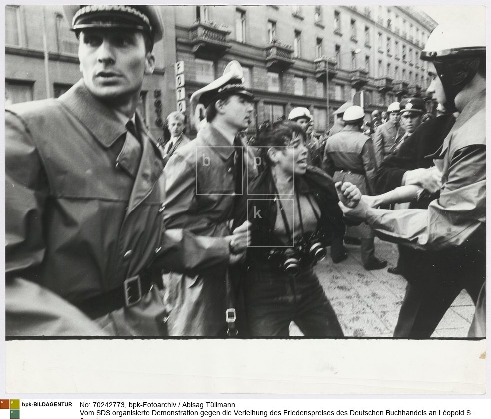 Drei Polizisten hindern die Fotografin Erika Sulzer-Kleinemeier an der Dokumentation der Kämpfe zwischen Polizei und Demonstranten vor dem Frankfurter Hof
Rückseitenbeschriftung von Hand der Fotografin: "Buchmesse, Sept. 68"
Rückseitenbeschriftung von anderer Hand: "Verhaftung der Fotografin Erika Sulzer-Kleinemeier<BR>Aufnahmedatum: 22.09.1968<BR>Material/Technik: Foto / Silbergelatine auf Barytpapier<BR>Bildformat (Foto): 23,5 x 29,3 cm<BR>Aufnahmeort: Frankfurt am Main / Deutschland<BR>Inventar-Nr.: Tü 68/225-33a<BR>