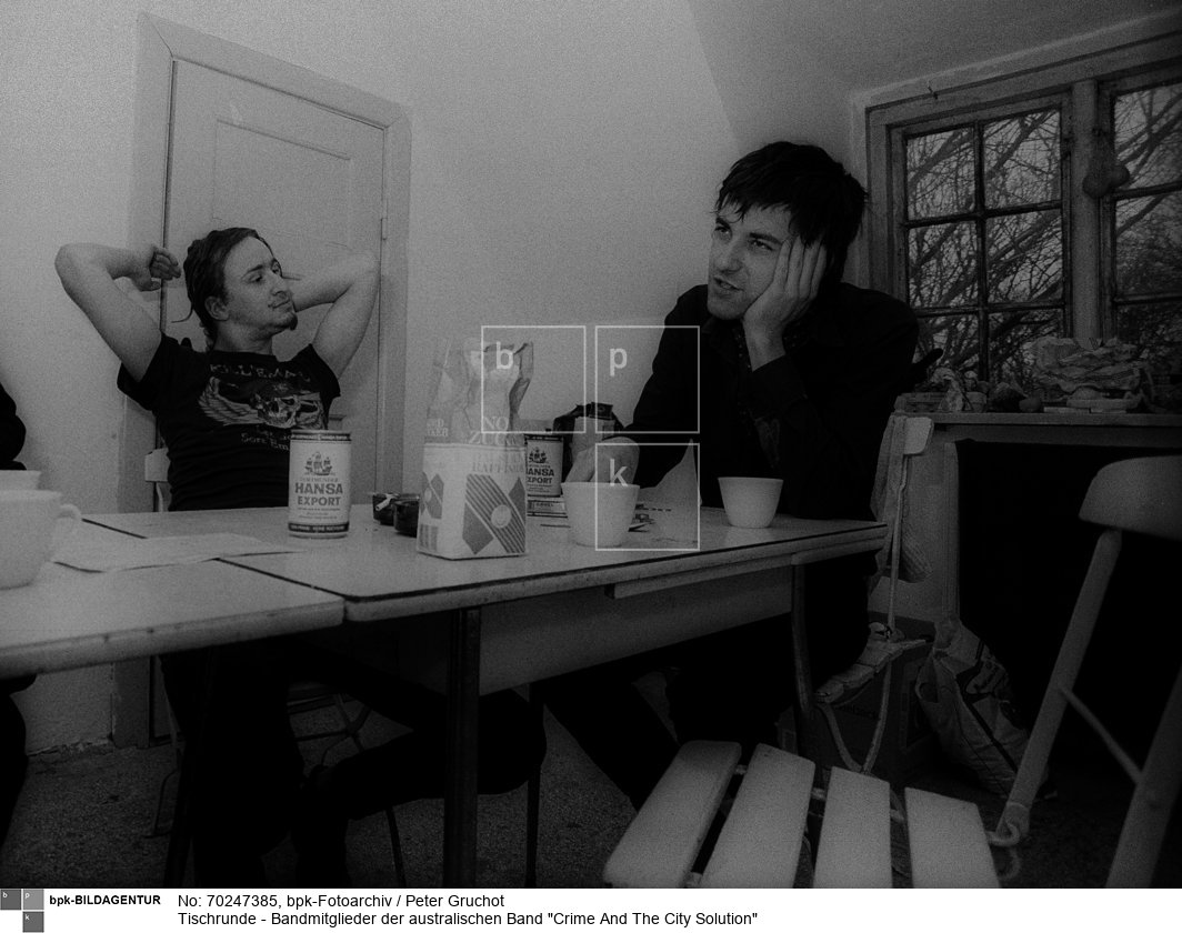 1979 vom Sänger und Songwriter Simon Bonney in Melbourne gegründet. Die erfolgreichste Phase der Indie-Rock-Band war von 1985-1991. Danach kam die erneute Auflösung der Band, bevor Bonney 2012 in Detroit zum dritten Mal eine Band unter dem Namen Crime & the City Solution gründete.

Variable Bandmitglieder: Simon Bonney (Gesang), Mick Harvey (Gitarre, Schlagzeug), Rowland S. Howard (Gitarre), Harry Howard (E-Bass), Epic Soundtracks (Schlagzeug), Bronwyn Adams (Geige), Chrislo Haas (Synthesizer), Alexander Hacke (Gitarre) und Thomas Stern (E-Bass)<BR>Aufnahmedatum: 04.05.1988<BR>Material/Technik: Foto<BR>Aufnahmeort: Emmelsbüll (Schleswig-Holstein)<BR>