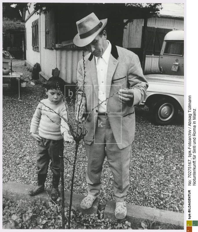 Ein Mann und ein Junge begutachten einen frisch gepflanzten Baum<BR>Aufnahmedatum: Mai 1971<BR>Material/Technik: Foto / Silbergelatine auf Barytpapier<BR>Bildformat (Foto): 29,3 x 23,3 cm<BR>Aufnahmeort: Mainz / Deutschland<BR>Inventar-Nr.: Tü 71/056-39<BR>