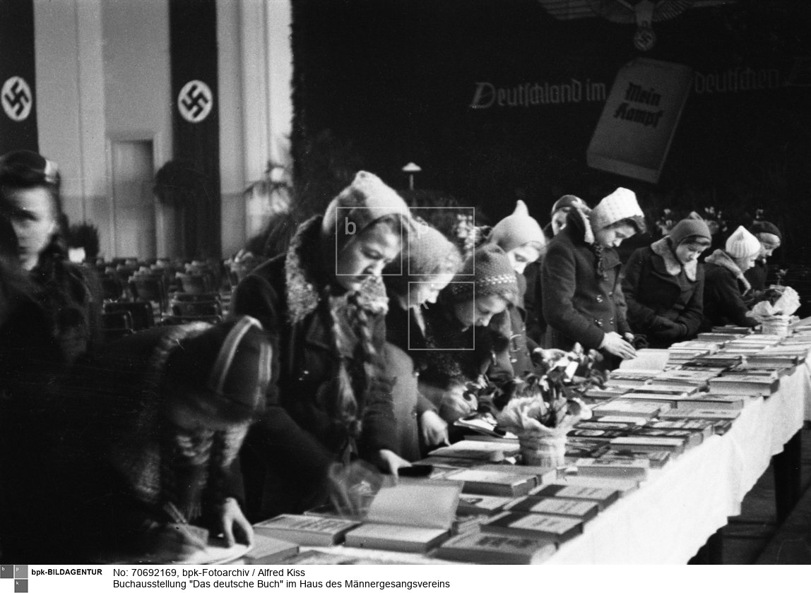 Die Ausstellung wurde am 9. Januar 1940 eröffnet. Veranstalter: Reichspropagandaamt Posen, Außenstelle Lodsch ; über dem Podium die Parole "Deutschland im deutschen Buch!"<BR>Aufnahmedatum: Januar 1940<BR>Material/Technik: Foto<BR>Aufnahmeort: Lodz (Lodsch, 1940-45 Litzmannstadt), Reichsgau Posen (1939-40), Reichsgau Wartheland (1940-45), Deutsches Reich (durch Annexion) / Łódź, Polen<BR>Inventar-Nr.: Ki I/015/16<BR>
