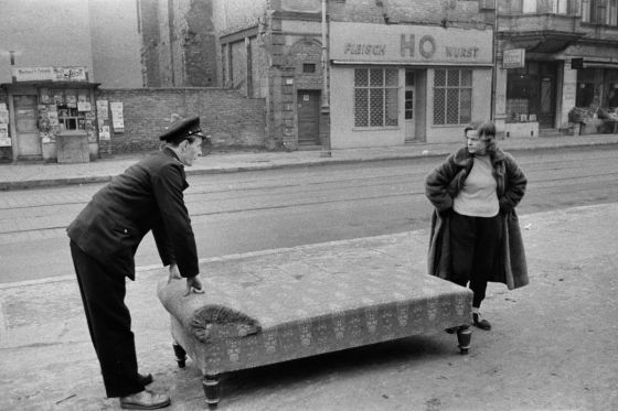 Ein Reichsbahner hilft einer älteren Dame beim Transport einer Chaiselongue durch die Straßen im Scheunenviertel
